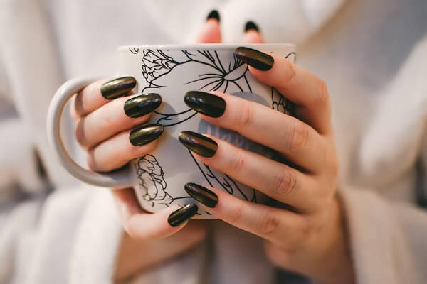 Women with Black polished nails holding cup