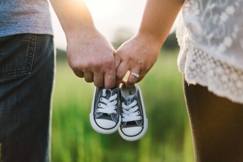 Couple holding kid's shoes in their hands